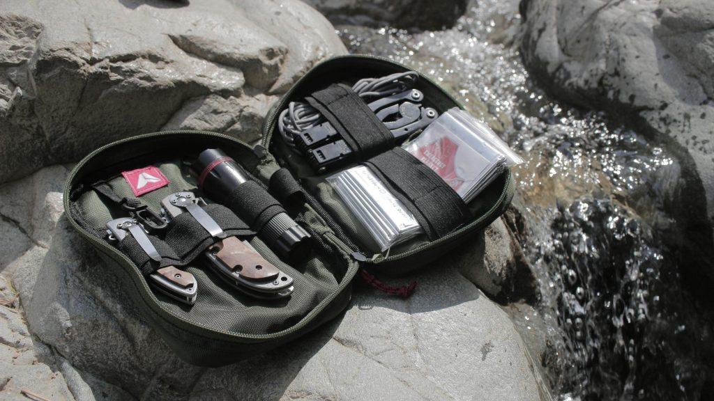 High-quality outdoor survival kit displayed on rocks near a flowing stream