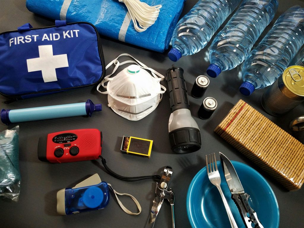 Flat lay of essential emergency survival kit items including first aid and water bottles.