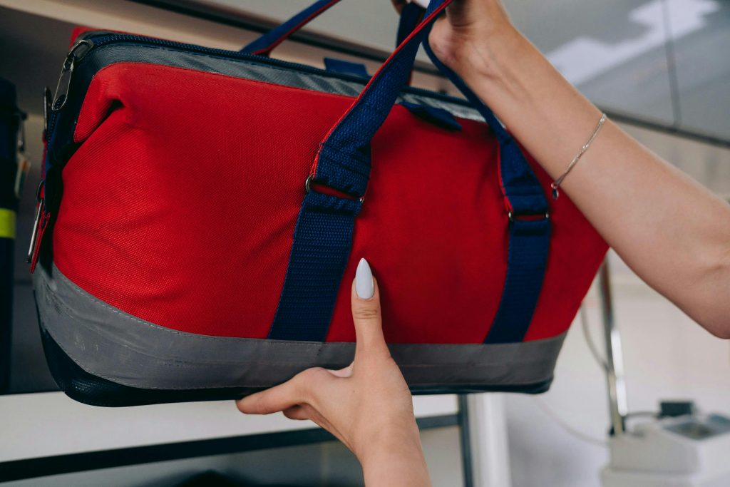 A paramedic securing a red emergency medical bag on a shelf inside an ambulance.