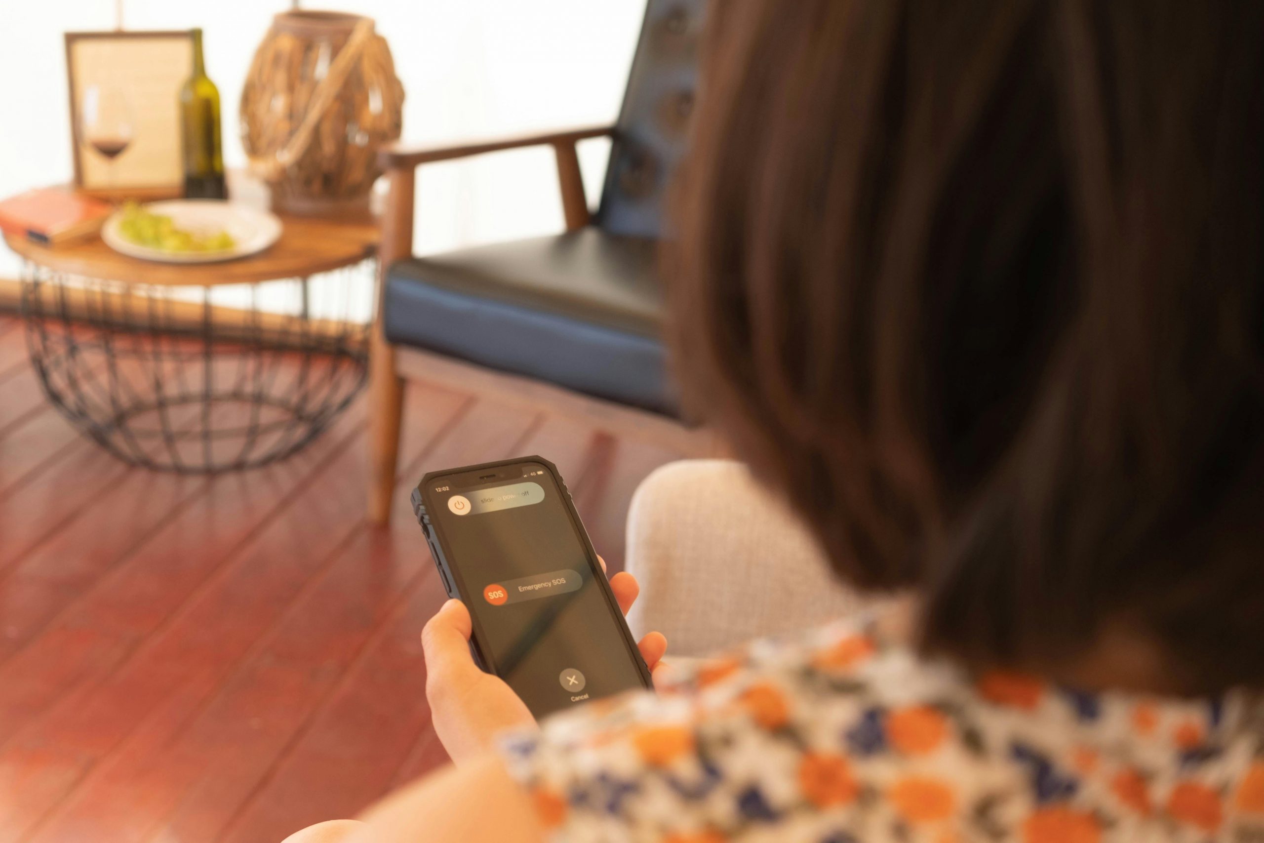 A person using a smartphone's SOS emergency feature indoors with a cozy background.
